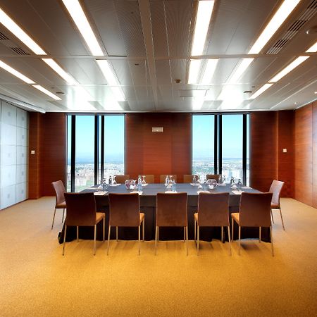 유로스타 마드리드 타워 외부 사진 The photo shows a modern conference room or meeting space. It features a large rectangular table surrounded by several leather chairs. The room has wooden paneling and large windows that let in natural light, providing a view of the outside landscape