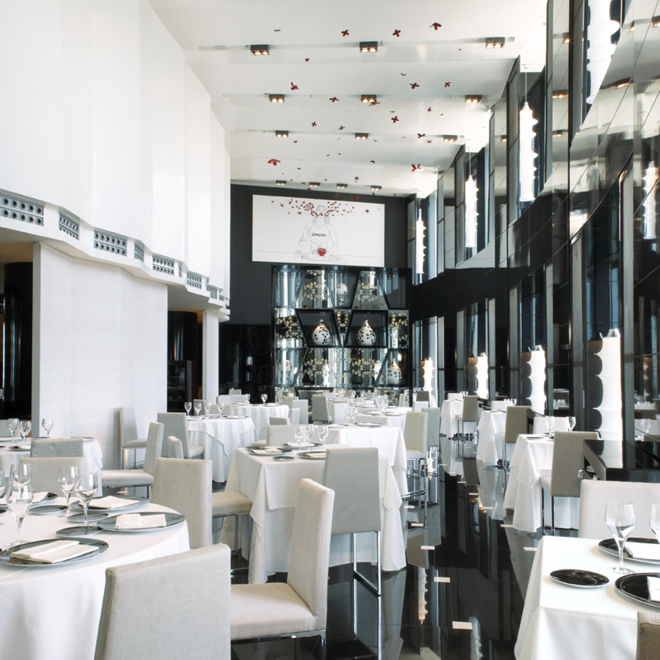 유로스타 마드리드 타워 외부 사진 The photo shows a modern and elegant restaurant interior. The space features tables covered with white tablecloths, arranged neatly with plates and glassware. The decor includes large glass windows that allow natural light to fill the room, and the w