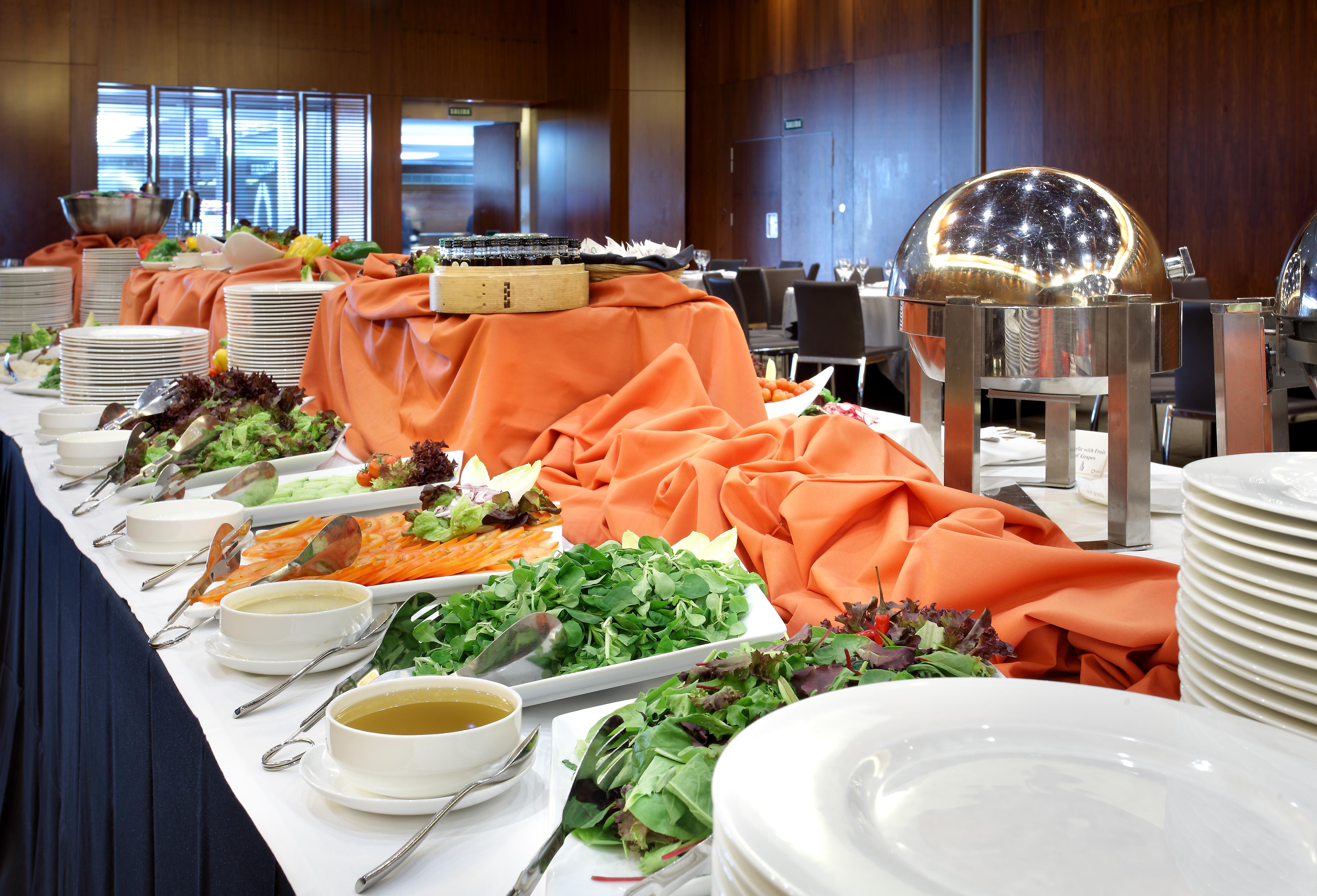 유로스타 마드리드 타워 외부 사진 The photo shows a buffet table set up for a meal. The table is covered with an orange cloth and features a variety of food items. There are platters of greens and salads, as well as bowls of soup or dressing. A metal chafing dish is present, likely c