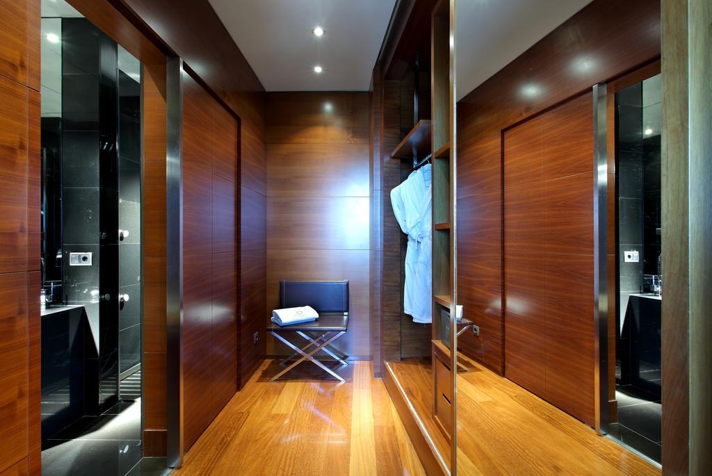 유로스타 마드리드 타워 외부 사진 The photo shows a stylish interior space that appears to be a modern changing area or dressing room. The walls are made of polished wood, giving a warm, elegant feel. There are several closed doors, indicating private spaces such as lockers or bathro