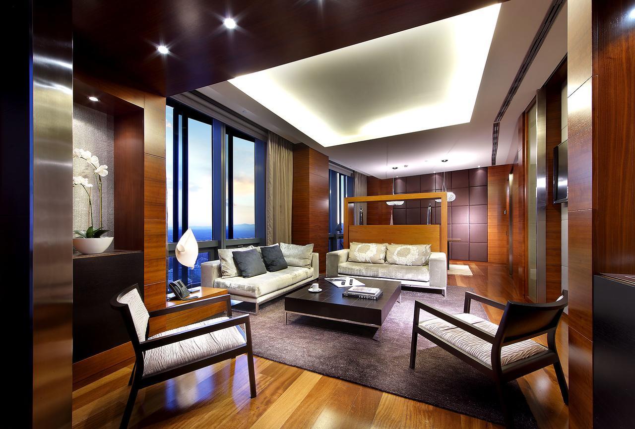 유로스타 마드리드 타워 외부 사진 The photo depicts a modern and elegantly designed living room. The space features large windows that allow natural light to flood in, showcasing a beautiful view outside. The flooring is polished wood, and the color palette incorporates warm tones, i