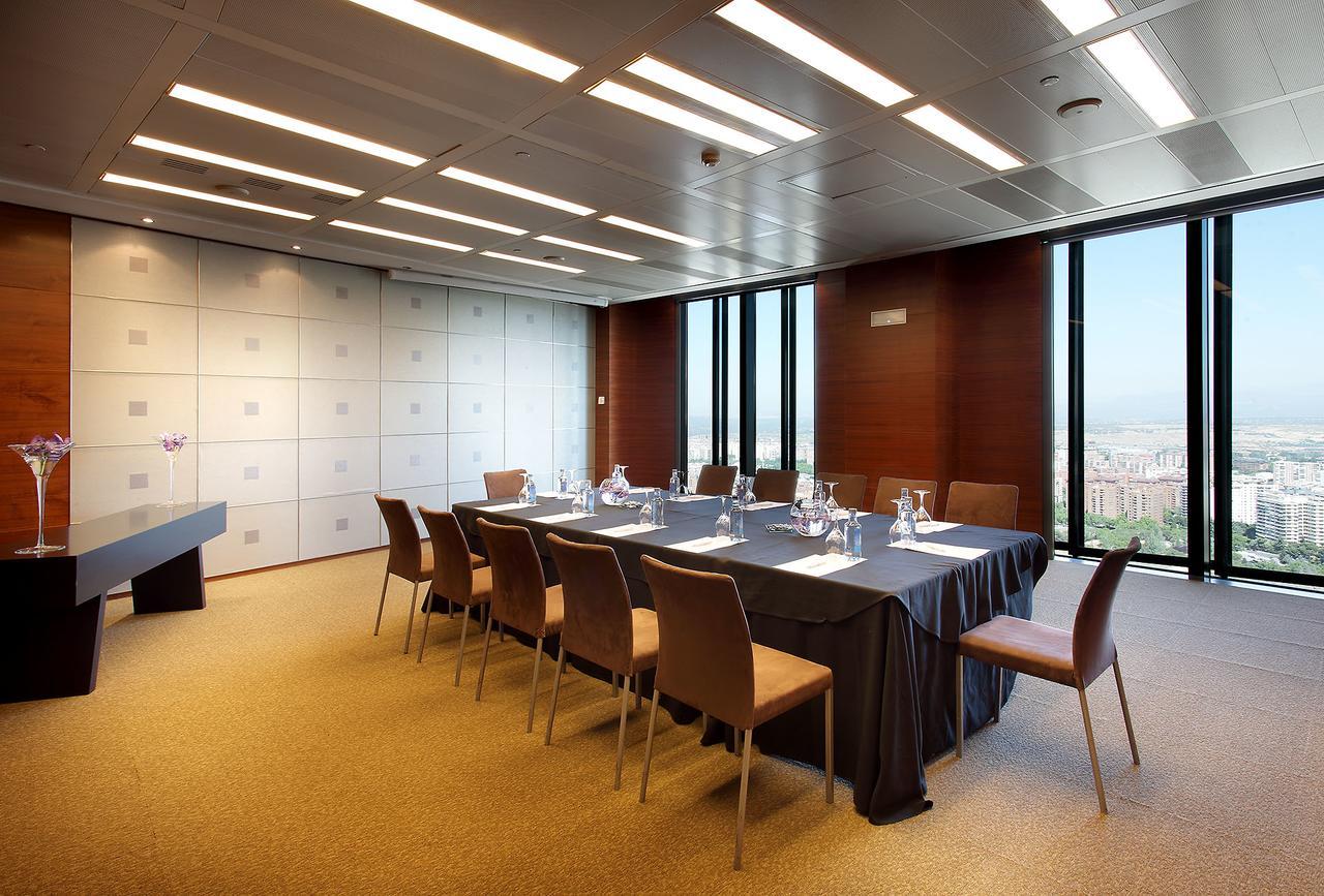 유로스타 마드리드 타워 외부 사진 The photo shows a modern conference room with a long table set up for meetings. There are several chairs around the table, and the table is covered with a dark tablecloth. On the table, there are glass pitchers and cups, indicating it is prepared for