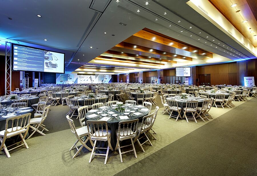 유로스타 마드리드 타워 외부 사진 The photo shows a spacious banquet hall or conference room set up for an event. There are several round tables arranged across the floor, each with elegant table settings, including plates, cutlery, and glasses. The decor features neutral tones, and 